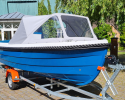 Motorboot Phantom 500 Classic in der Sonderlackierung Azurblau mit grauer Sprayhood. Das Boot steh auf einem neuem Bootstrailer mit Sliprollen und Bugwinde.