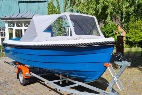 Motorboot Phantom 500 Classic in der Sonderlackierung Azurblau mit grauer Sprayhood. Das Boot steh auf einem neuem Bootstrailer mit Sliprollen und Bugwinde.